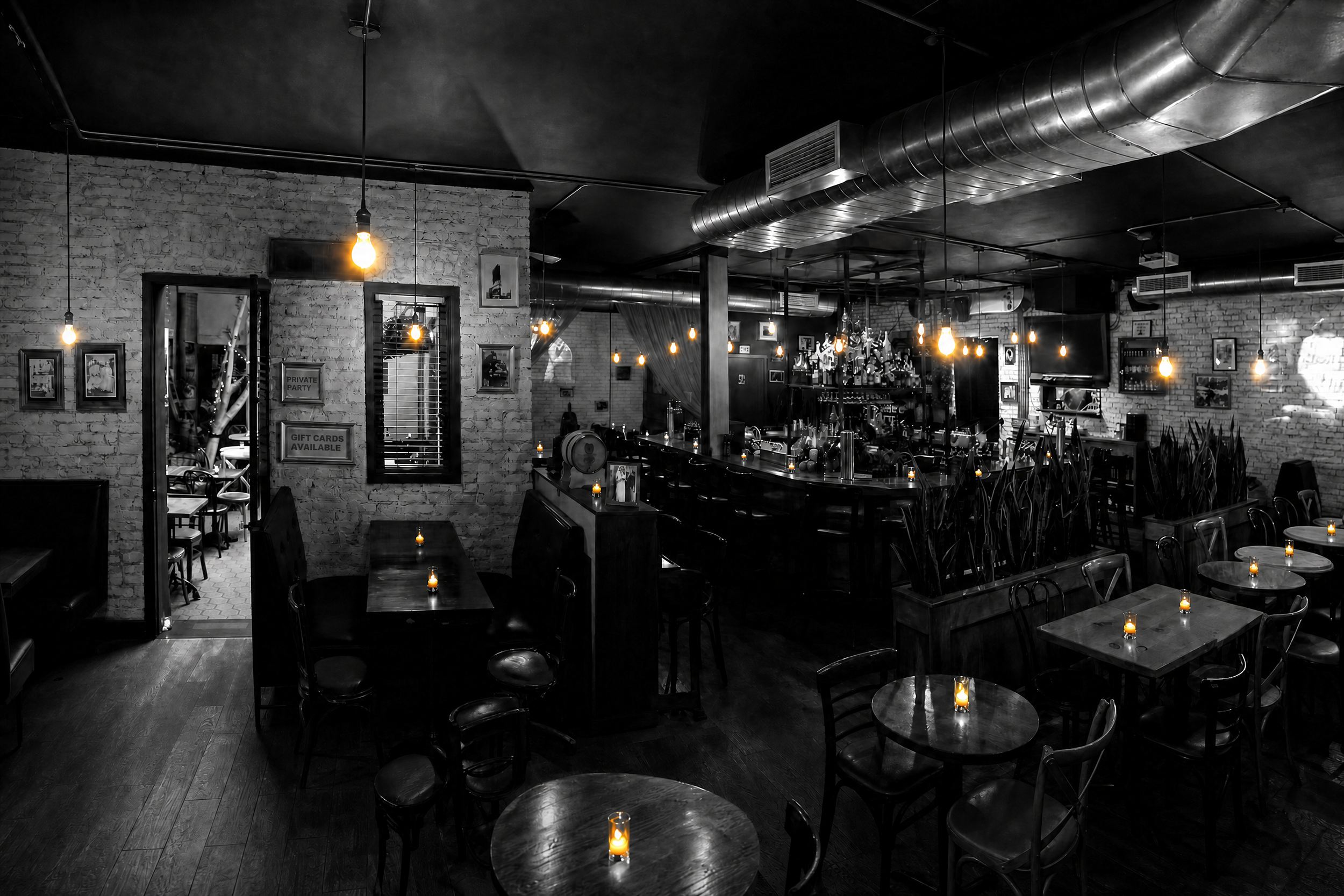 Black-and-white view of BEA's brick-lined restaurant and cocktail bar, illuminated by warm pendant lights
