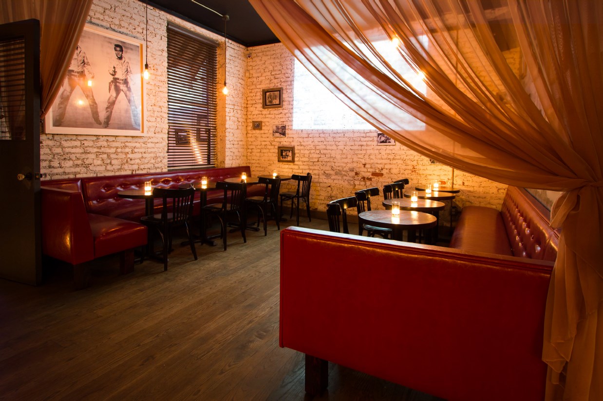 Wide view of BEA's Lounge with red banquettes, candlelit tables, and amber drapery